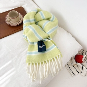 Close-up of thick striped wool scarf with long white fringes and soft knitted texture