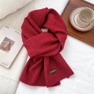 Close-up of dark red chunky knit scarf with vertical stripes and stylish logo tag