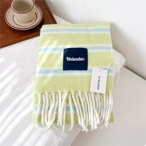Detail of soft striped wool scarf with fringe and brand label on white bedding