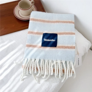 Detail of blue and orange striped wool blend scarf with white fringe and brand label