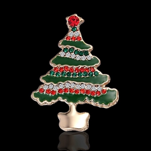 Close-up of golden Christmas tree brooch with green enamel and colorful rhinestones