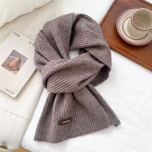Close-up of ribbed knit texture on brown scarf with a leather brand patch detail