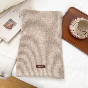 Close-up of ribbed knit texture in oatmeal beige with a brown leather logo patch detail
