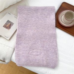 Detailed knit texture of lavender scarf with Eggdoris embroidery label on white fabric