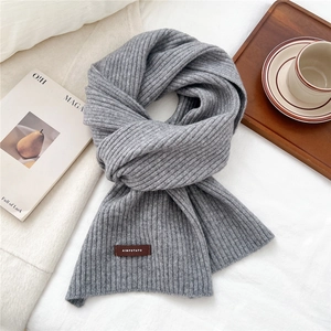 Detailed macro view of the grey ribbed knit scarf with a premium brown leather logo patch