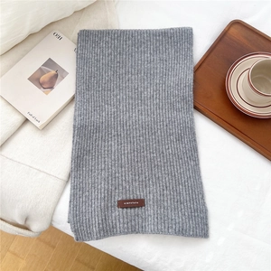 Detailed texture of gray knitted scarf with vertical stripes and premium brown leather label
