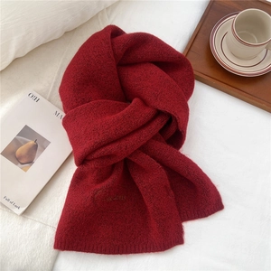 Close-up of wine red knitted scarf texture with oval embroidered logo detail