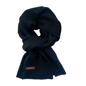 Minimalist black knitted scarf for women with vertical ribbed texture and leather tag