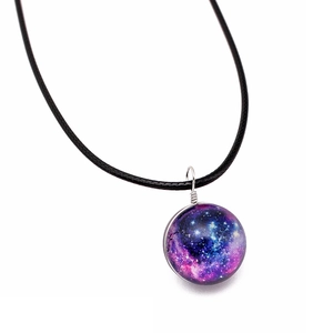 Macro shot of a handmade glass galaxy ball pendant with blue-purple starry nebula patterns