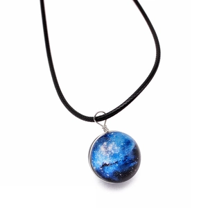 Macro detail of a double-sided glass universe ball necklace with blue galaxy pendant