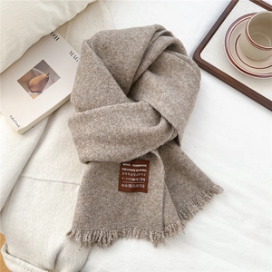 Dettaglio sciarpa di lana marrone con etichetta fatta a mano e nappe decorative