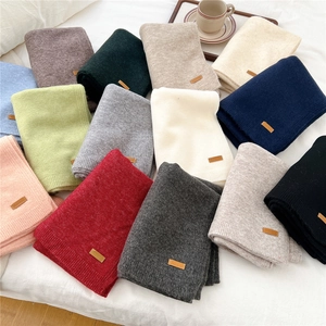Multiple colors of knitted scarves featuring stylish leather tags on soft ribbed edges