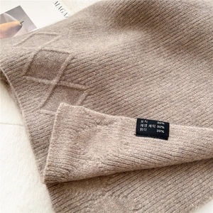 Detailed macro shot of brown argyle knit scarf texture and material composition tag