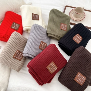 Detailed close-up showing thick rib-knit texture and leather labels of wool scarves