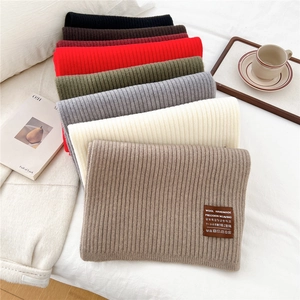 Classic vertical stripe knitted scarf for women in multiple warm colors on white bed