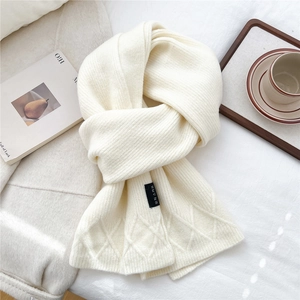 Detail of cream knit scarf featuring vertical ribbed texture and argyle pattern accents