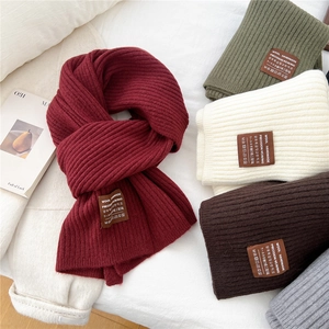 Detailed macro view of thick striped knit wool scarves with premium leather brand labels