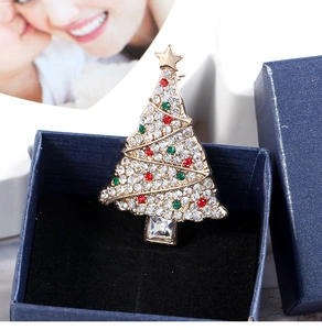 Detailed view of a gold Christmas tree brooch with colorful rhinestones in a blue jewelry box