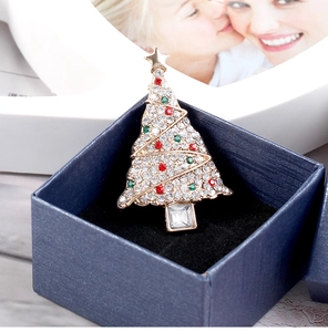 Close-up of a Christmas tree brooch with colorful zircons in a navy blue jewelry box