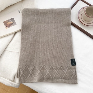 Detailed close-up of knitted oatmeal scarf featuring argyle patterns and fabric label