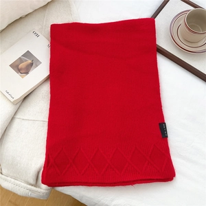 Detail of red knit scarf with argyle texture and brand label on white fabric
