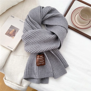 Close-up of thick light gray ribbed knit scarf with handmade leather brand label
