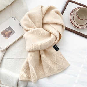 Detail of cream-colored knit scarf featuring rib texture and chic diamond pattern