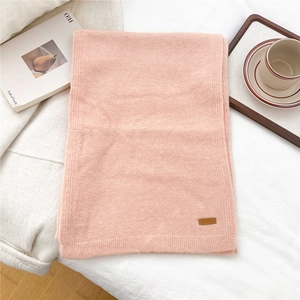 Detailed macro view of soft pink knitted scarf texture with premium brown leather label