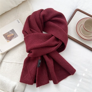 Macro detail of wine red knitted scarf with washing label on a cozy white background