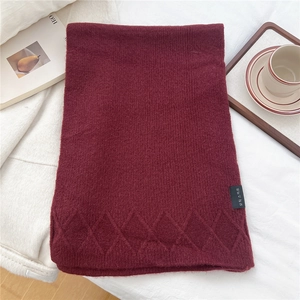 Detailed texture of burgundy diamond-pattern knit scarf with stylish woven brand tag