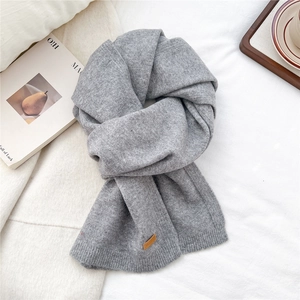 Detail showing the gray knitted scarf with a premium leather patch and soft texture