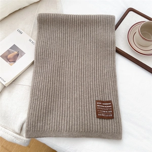 Close-up of ribbed knit scarf in oatmeal wool blend with premium brown leather label