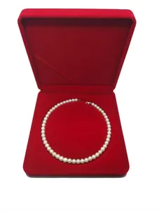 Detailed top view of a white pearl necklace inside a premium red velvet jewelry gift box