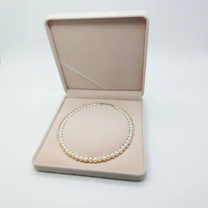 Detail of elegant white pearl necklace inside a soft beige velvet jewelry gift box