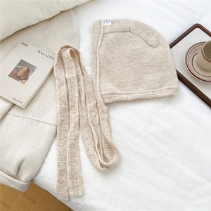 Detail of oatmeal knit balaclava hood showing thick texture and long scarf straps