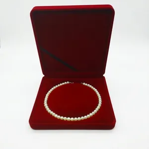Detailed view of a white pearl necklace inside a luxury red velvet jewelry gift box