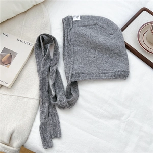 Detail of grey knitted hood scarf featuring thick yarn texture and white brand label