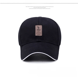 Detail of black cotton baseball cap with brown leather patch and white brim piping