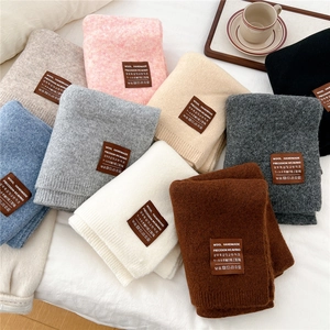 Close-up of assorted handmade wool scarves featuring brown leather brand tags