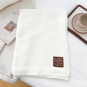 Detailed close-up of handmade wool scarf texture with premium brown leather brand tag