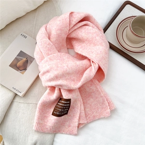 Close-up of pink knitted scarf showing soft wool texture and handmade craft label