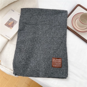 Close-up of dark grey knitted scarf with premium wool handmade leather label detail
