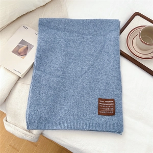 Close-up of gray-blue knitted scarf texture with premium handmade leather brand label