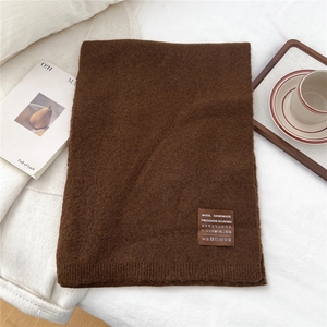 Detail of solid brown handmade wool scarf with precision weaving label and soft texture