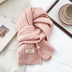 Dettaglio di sciarpa rosa chiaro a trecce con morbida texture e etichetta decorativa