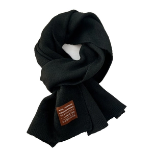 Black knit wool scarf for women with handmade leather tag on a clean white background