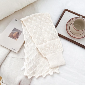 Detailed close-up of cream knit scarf featuring unique scale texture and ribbed edge detail
