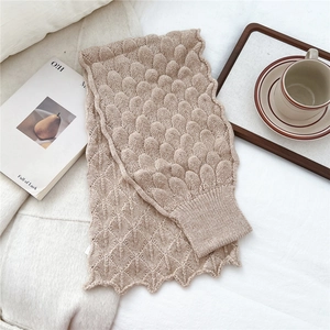 Close-up of oatmeal knit scarf showing thick fish-scale stitch texture and ribbed edge