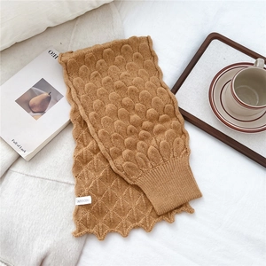 Detailed knit texture and ribbed cuff of a caramel fish-scale pattern knitted scarf