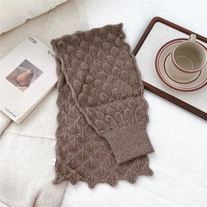 Detailed knit texture and wavy edge of a brown fish-scale pattern winter scarf